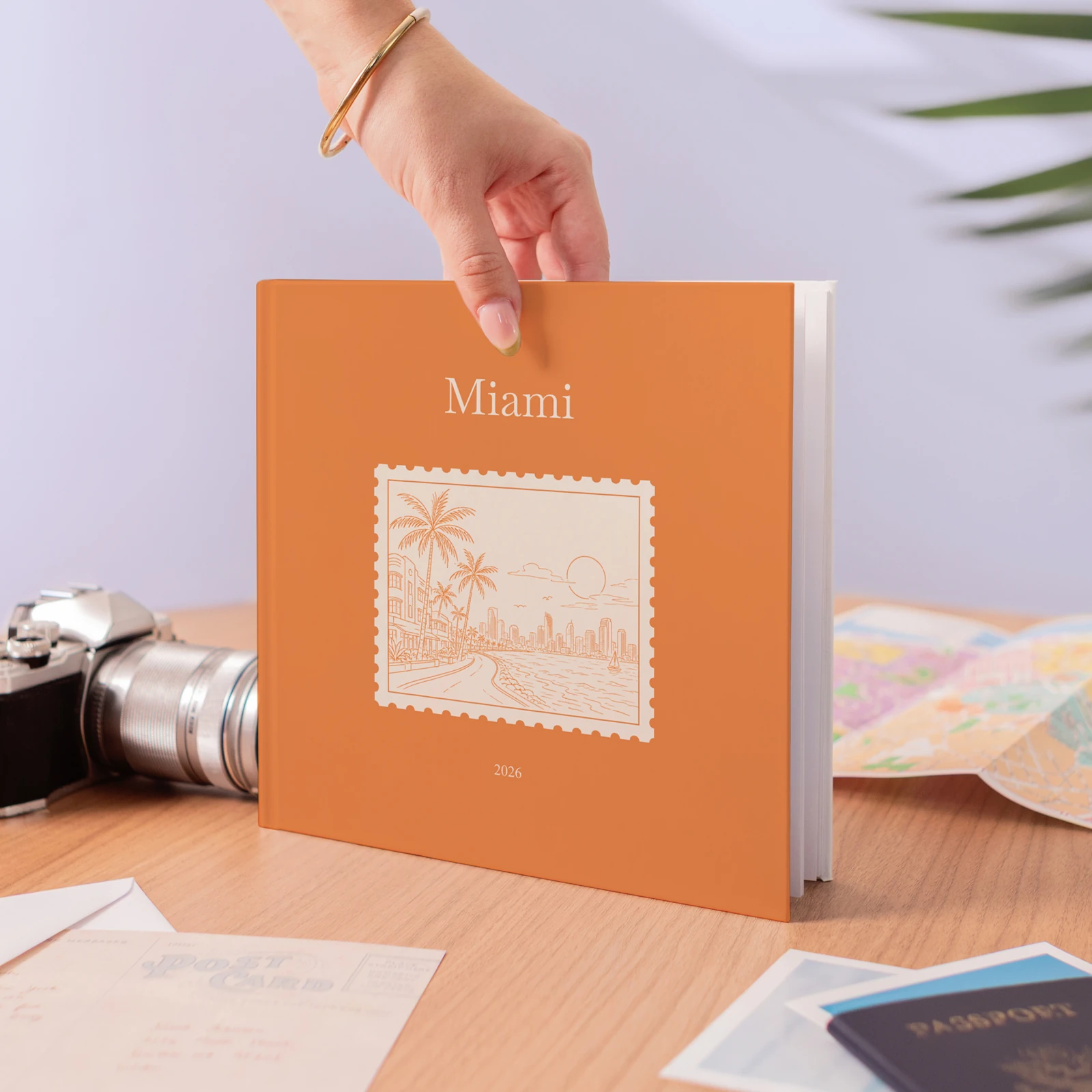 A Miami Travel Book held above a desk with a vintage camera and a folding map